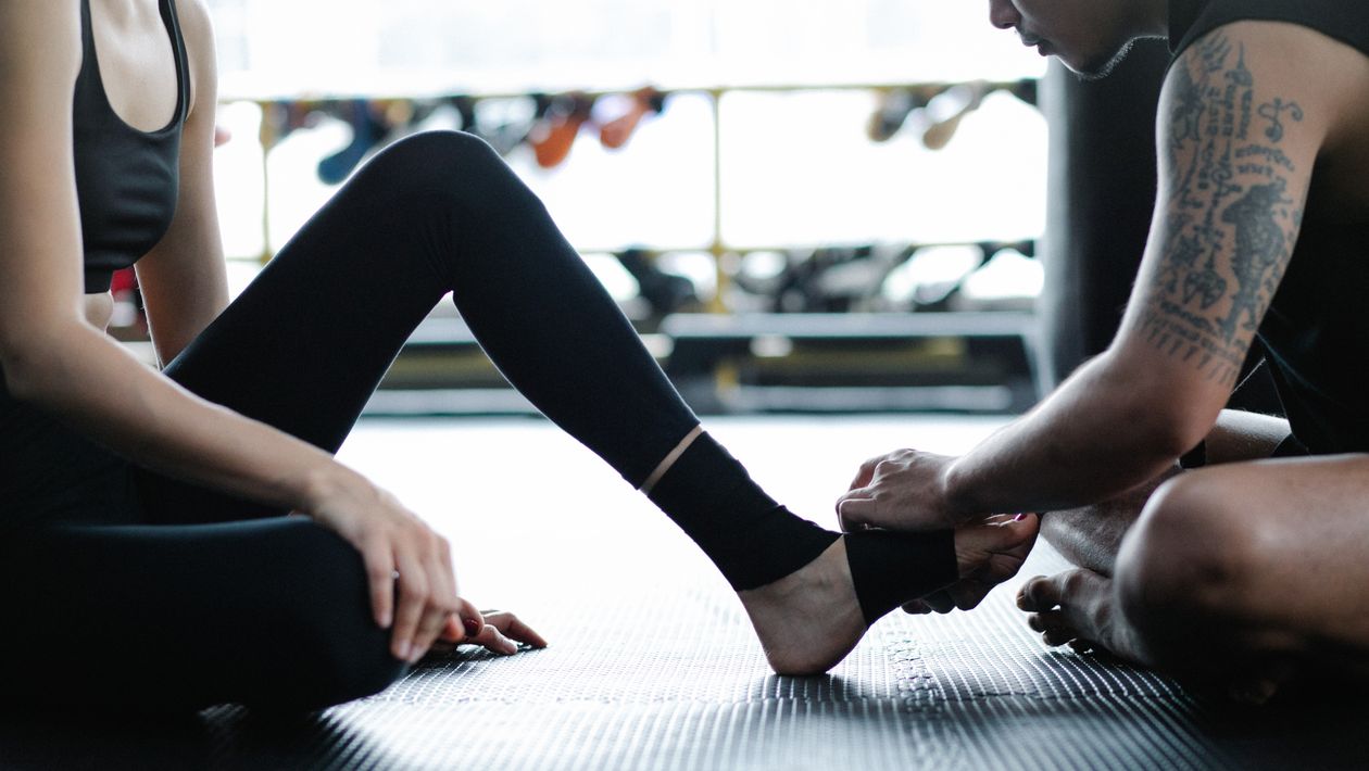 two adults in gym attire working on ankle support and mobility exercises