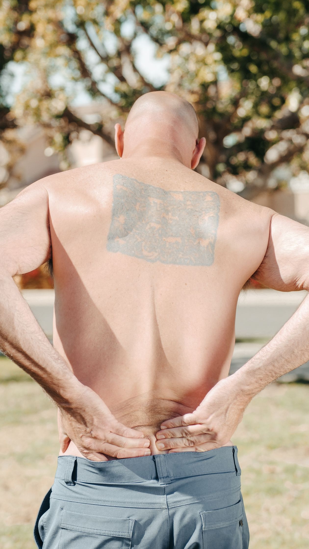 man holding his lower back outdoors showing chronic lower back pain