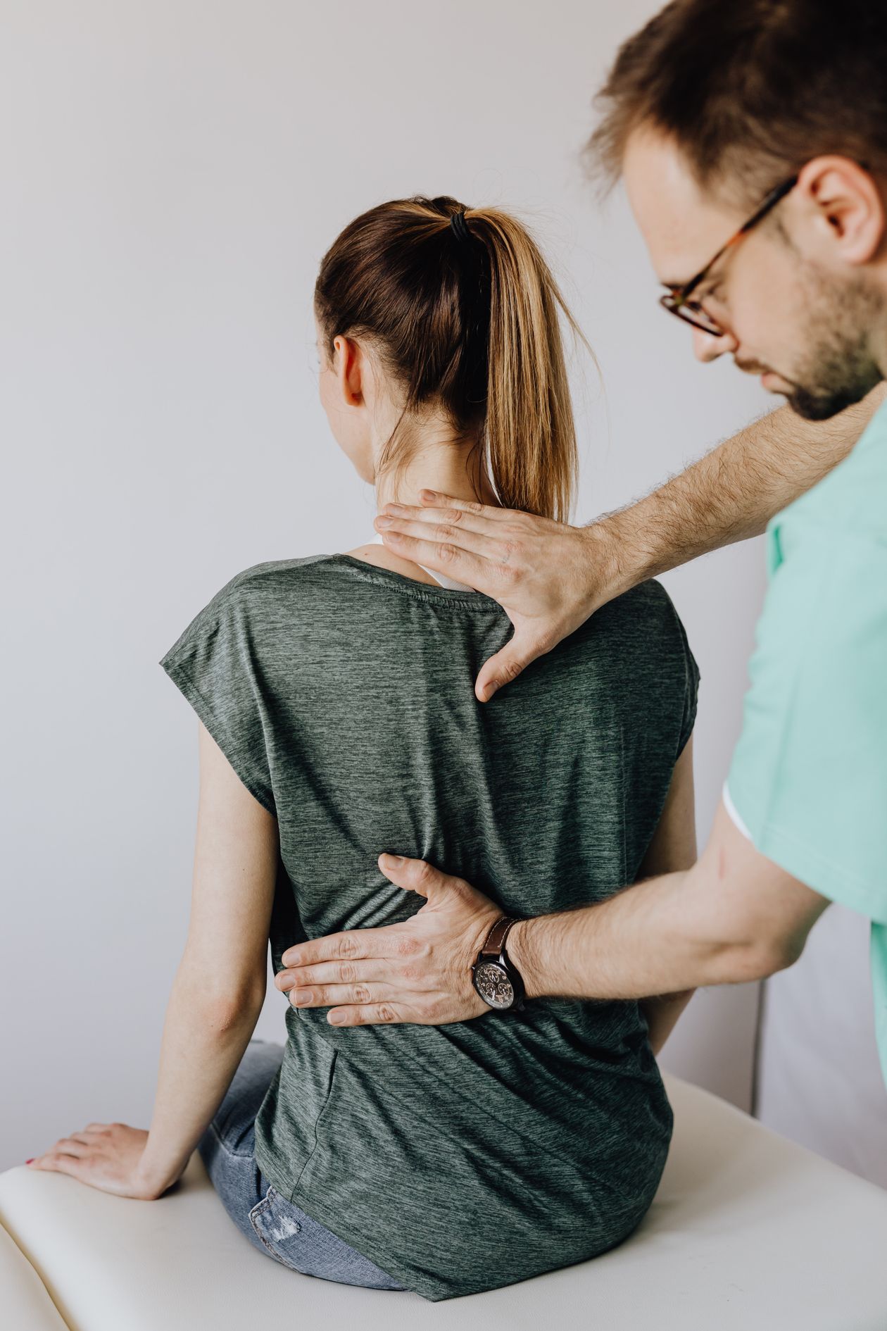 physiotherapist examining patient's spine and back posture in clinic assessment