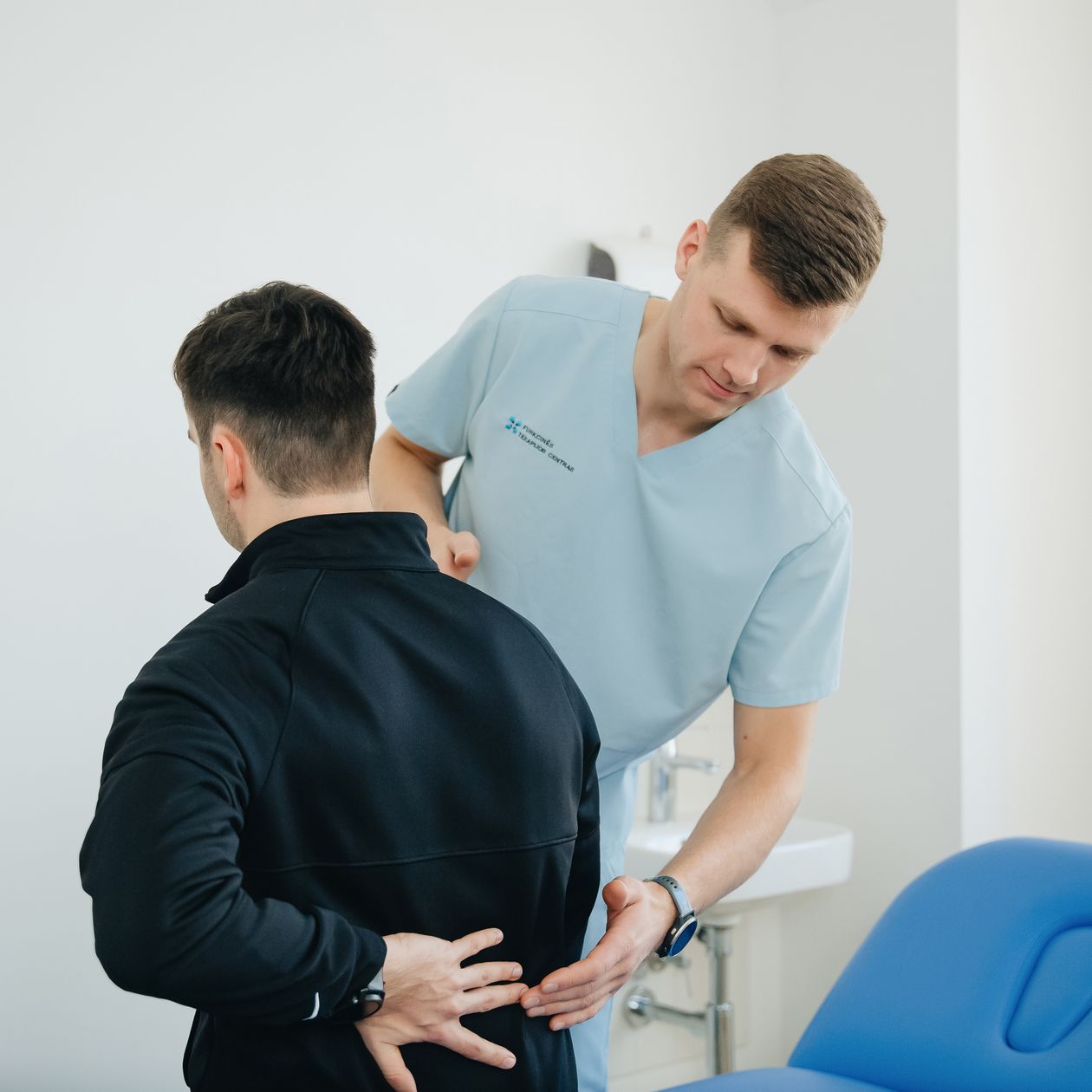 physiotherapist assessing a patient's back posture and spine alignment in clinic