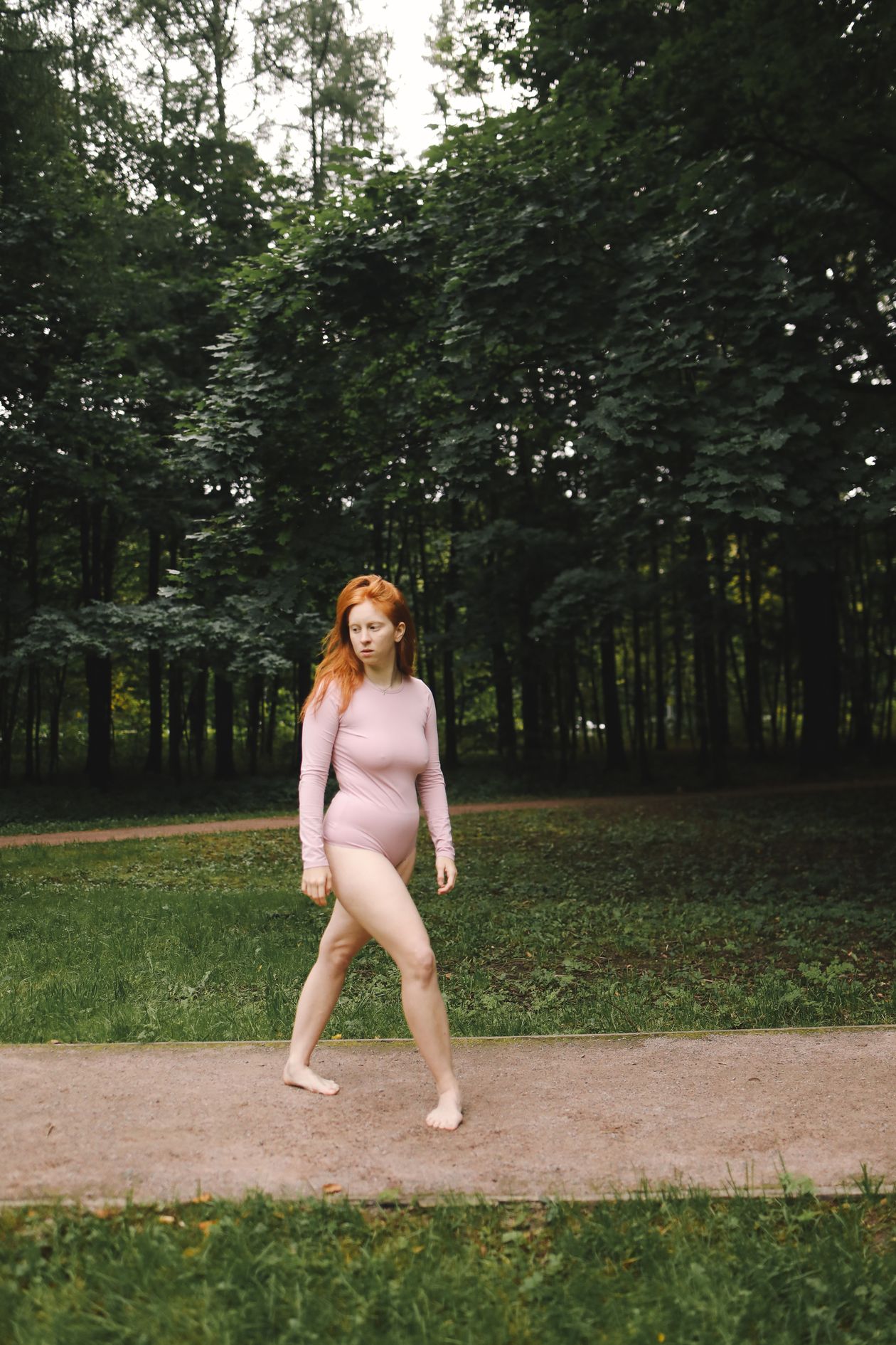 Woman walking barefoot through a green park showing natural foot movement and ground contact for proprioception and balance