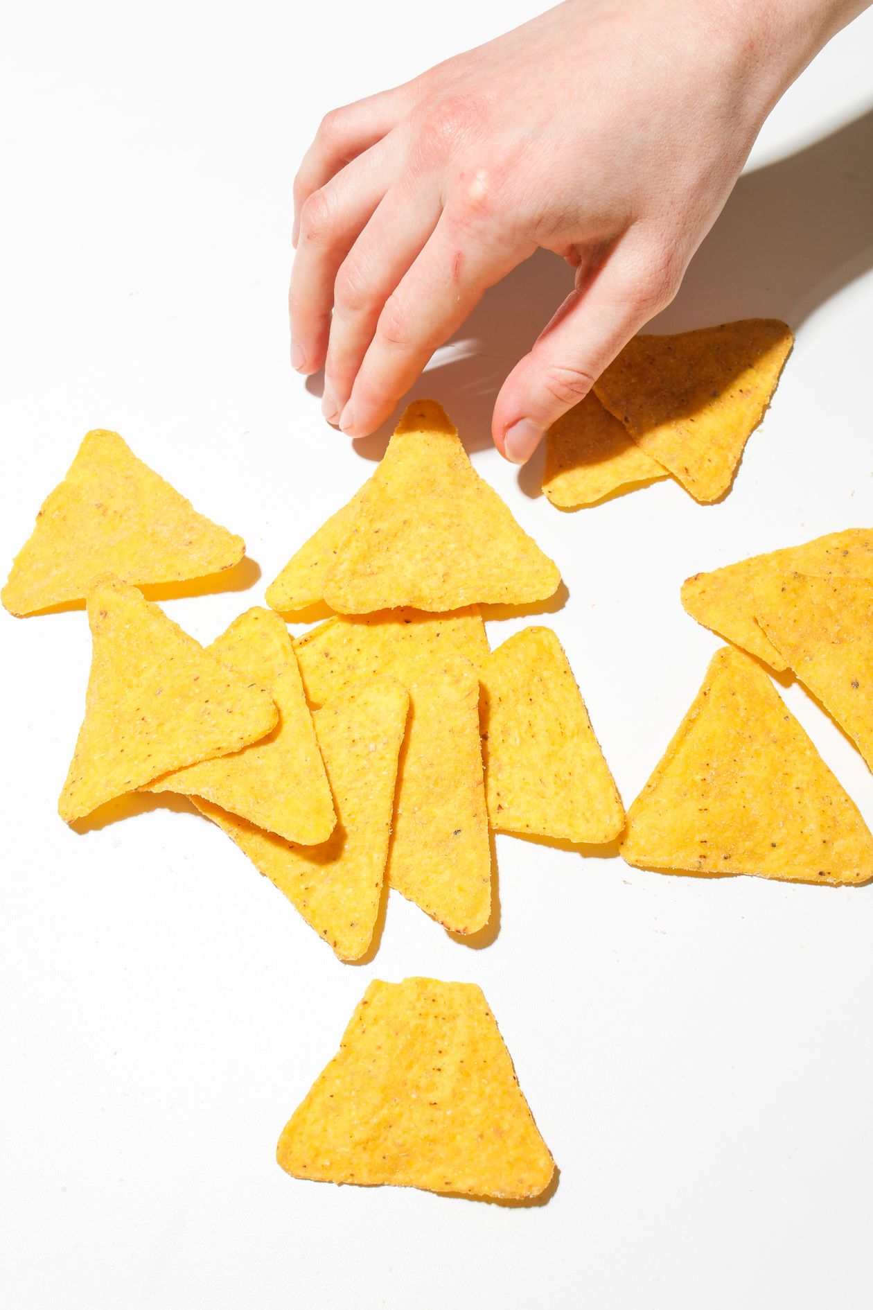 hand reaching for nacho chips showing snack foods that promote inflammation in adults with joint pain