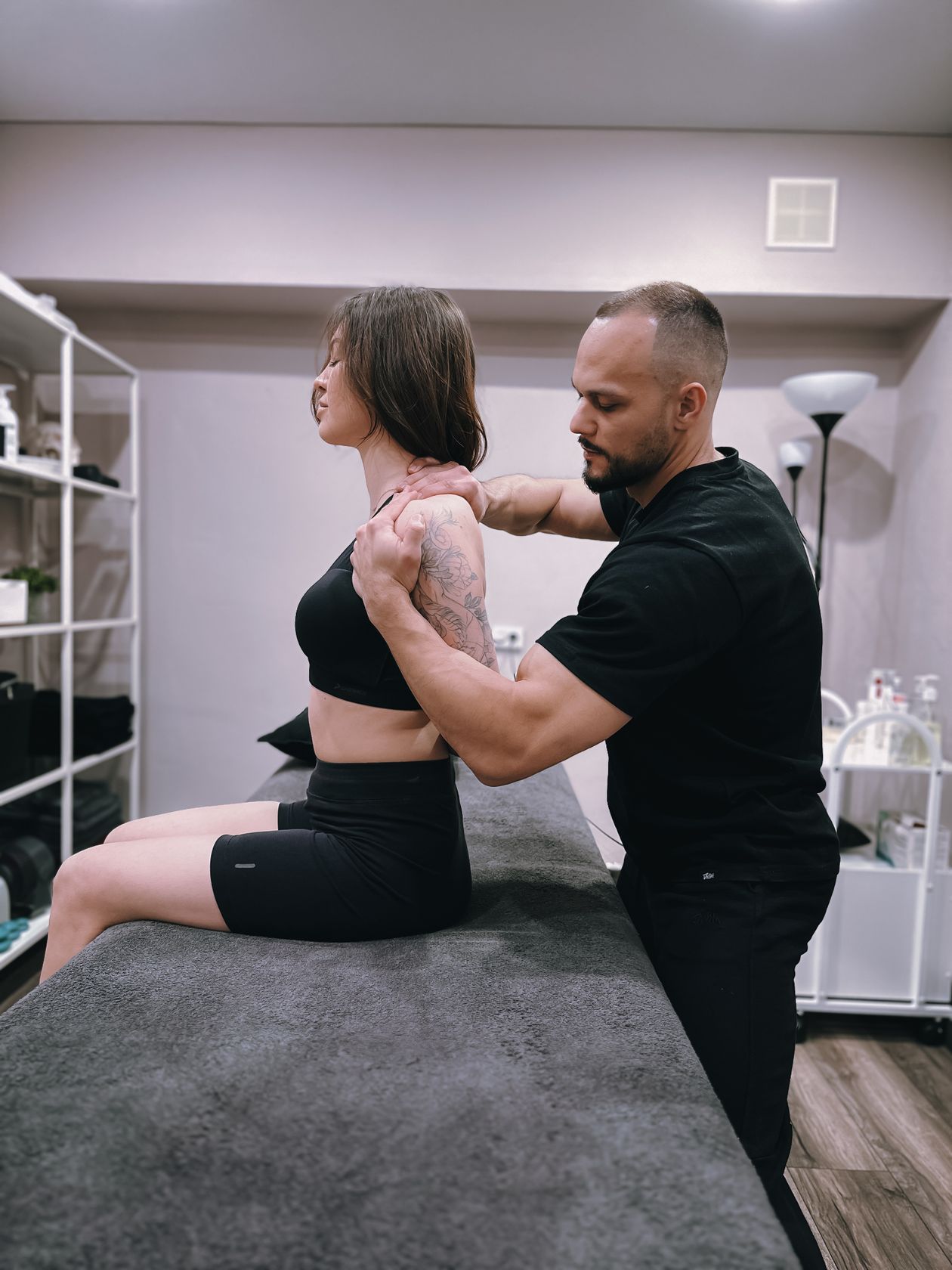 chiropractor adjusting female patient's shoulder in a clinical setting
