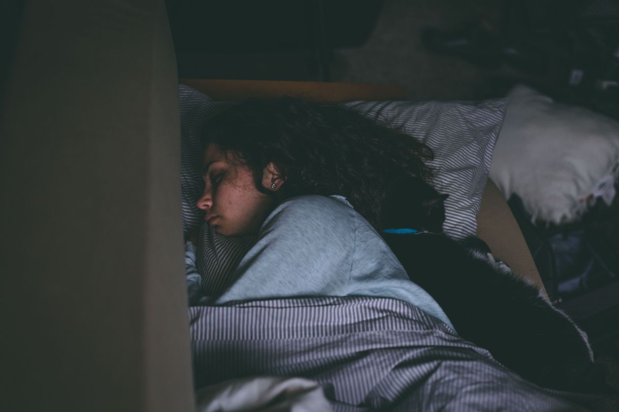 woman resting peacefully with a cat in a comfortable bedroom sleep environment
