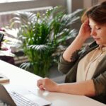 woman with bad posture sitting stressed at desk with laptop