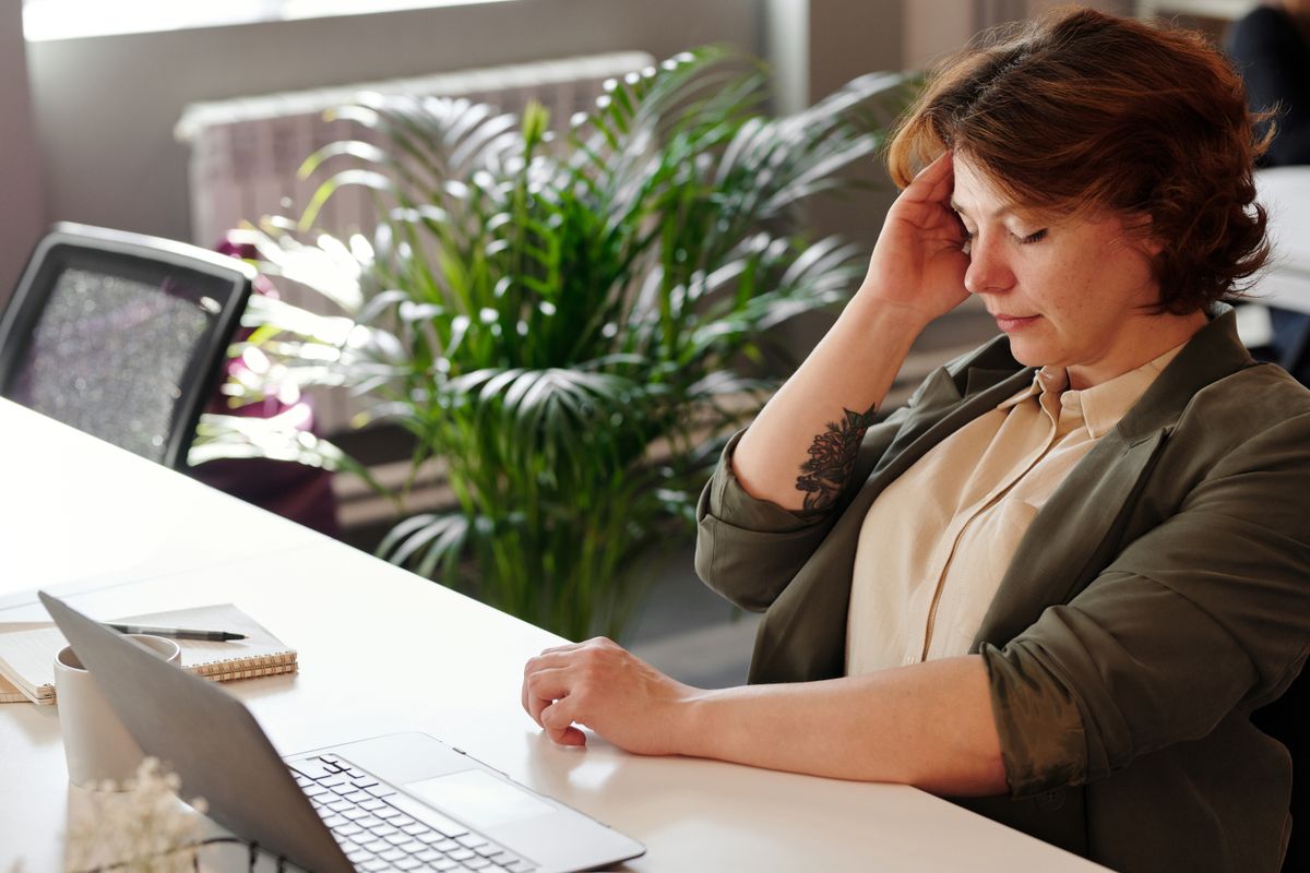 woman with bad posture sitting stressed at desk with laptop