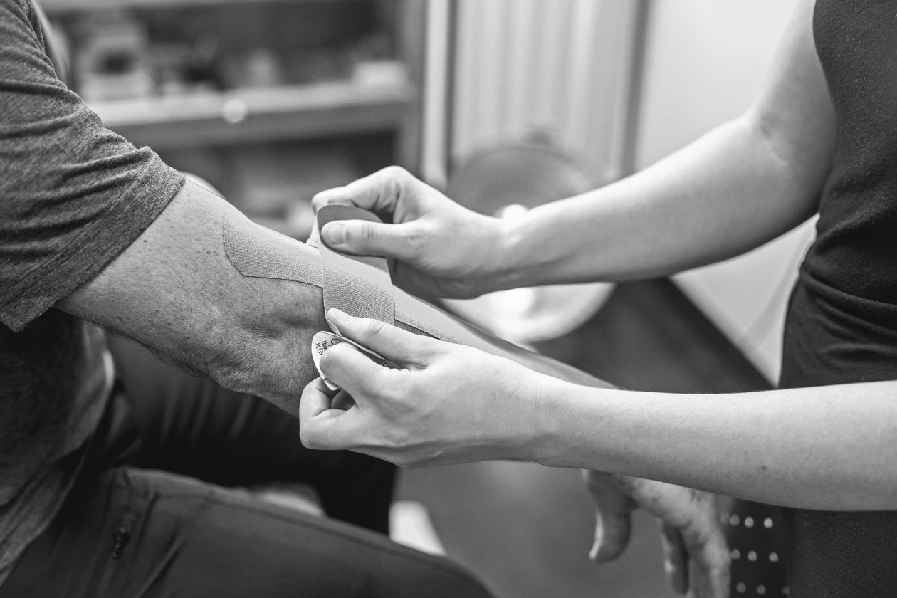 kinesiology tape being applied to an elbow for therapeutic support in tennis or golfer's elbow treatment