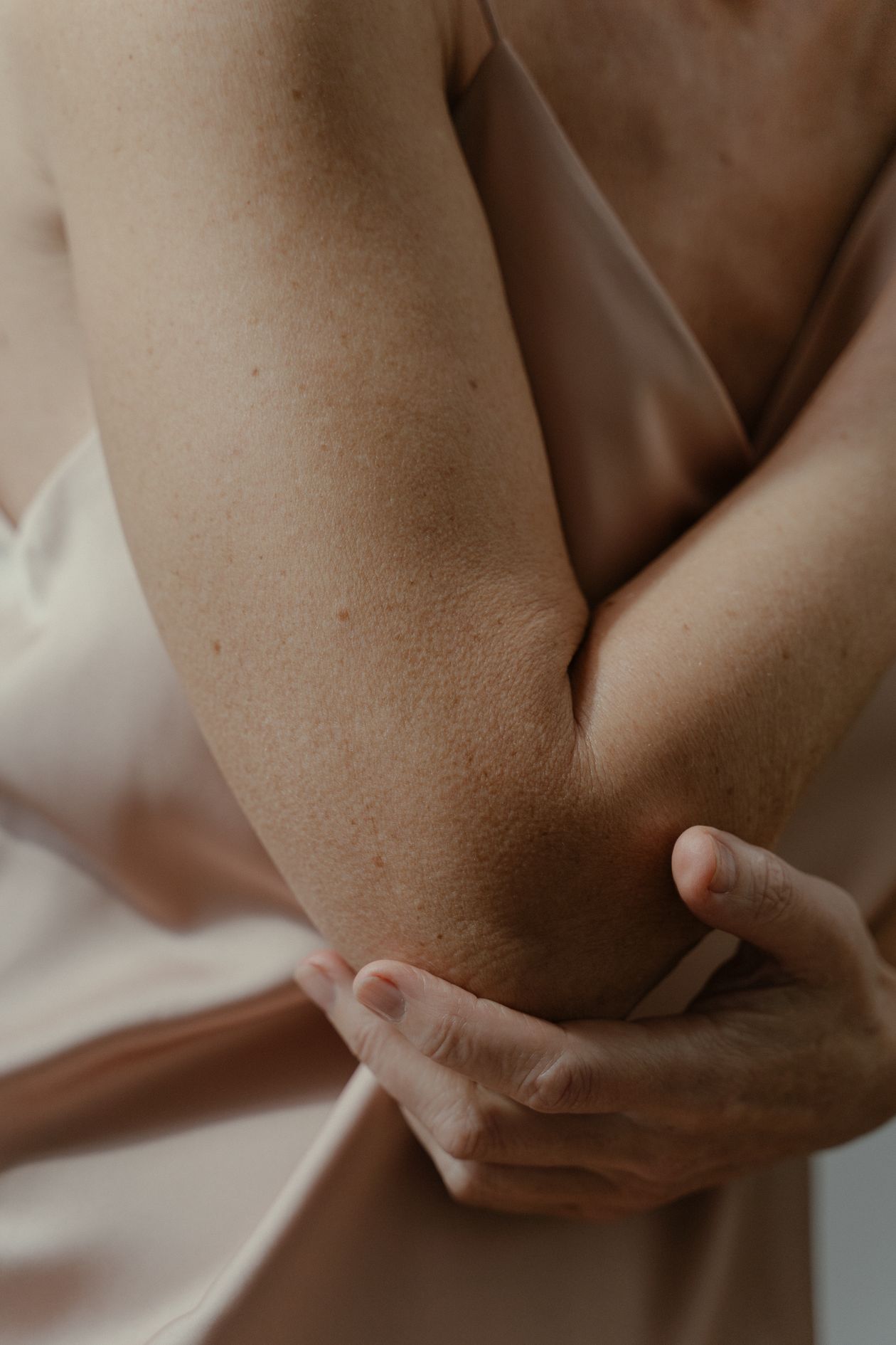 close-up of a person's arm touching the elbow showing elbow joint pain from lateral or medial epicondylitis