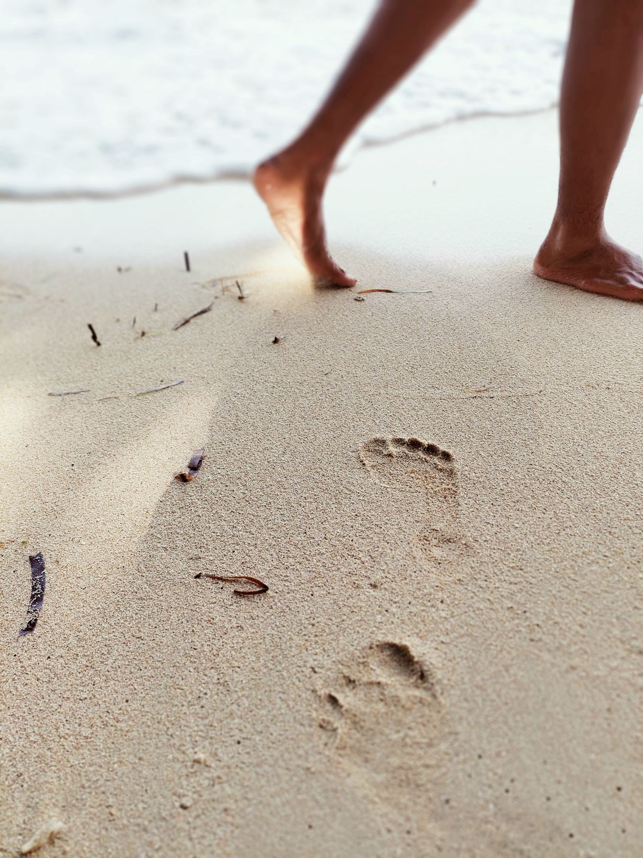 Close-up of bare feet on beach sand showing natural toe spread and foot position that barefoot shoes aim to restore