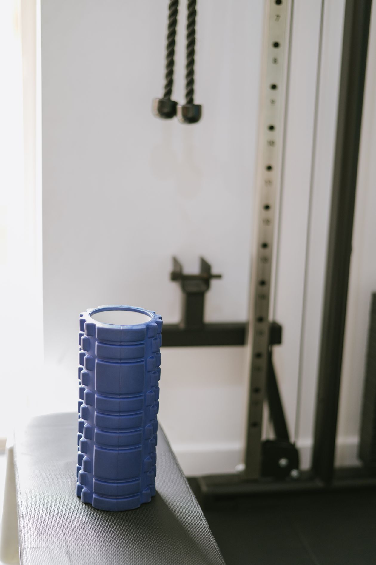 blue muscle roller on a gym bench showing foam rolling equipment for post-exercise muscle recovery