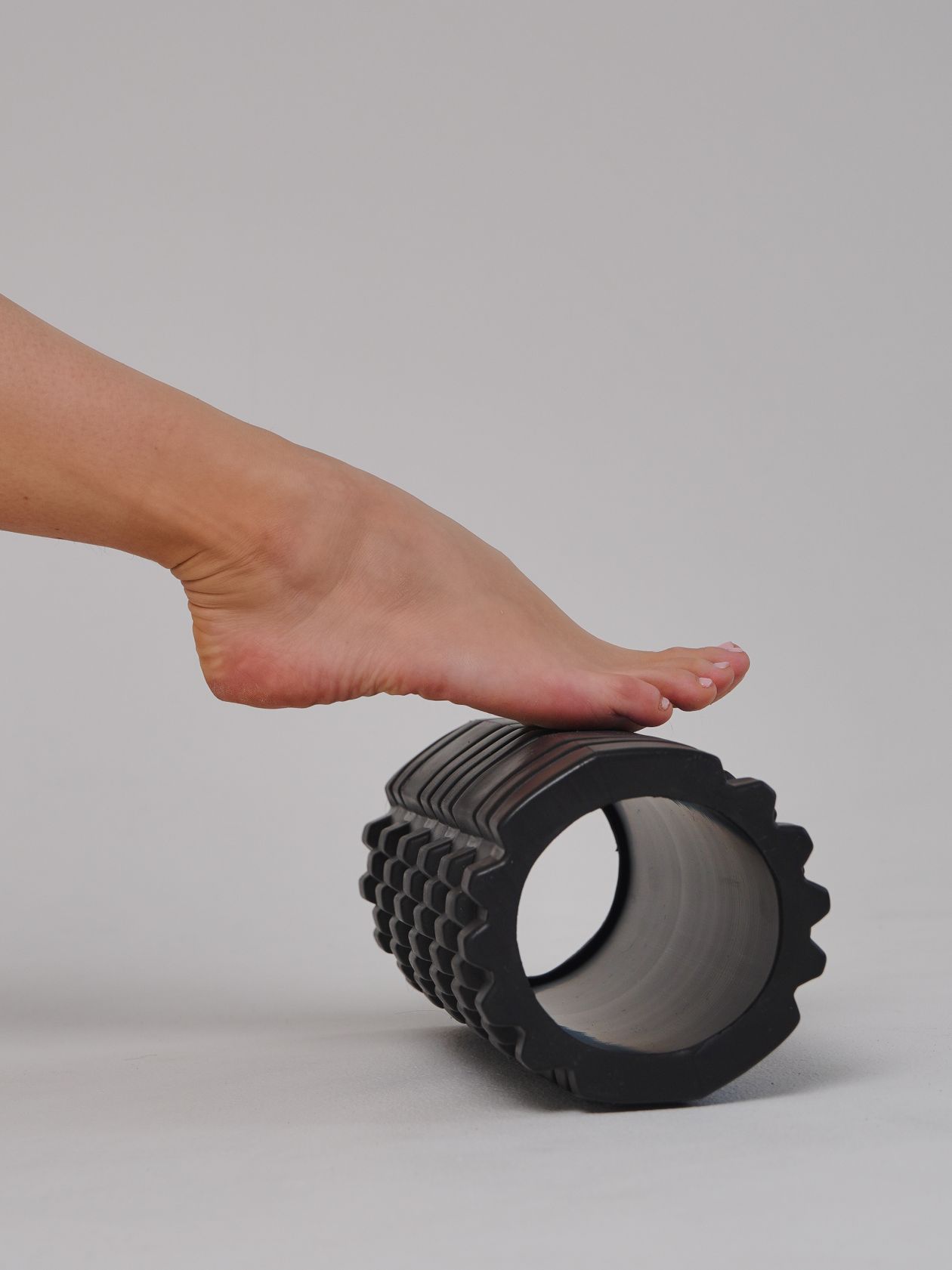 close-up of a foot placed on a foam roller during physiotherapy for plantar fascia and calf recovery