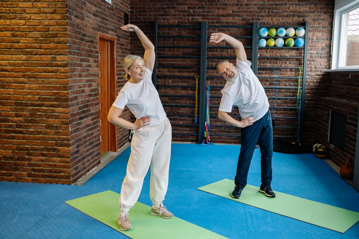 elderly couple stretching on yoga mats in home gym embracing healthy lifestyle