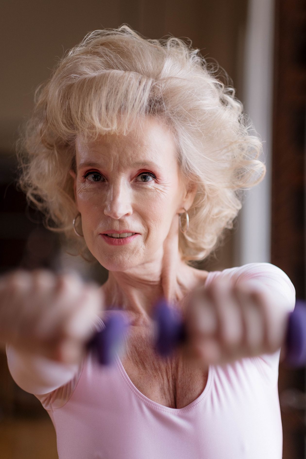 elderly woman exercising with dumbbells at home promoting fitness after 40