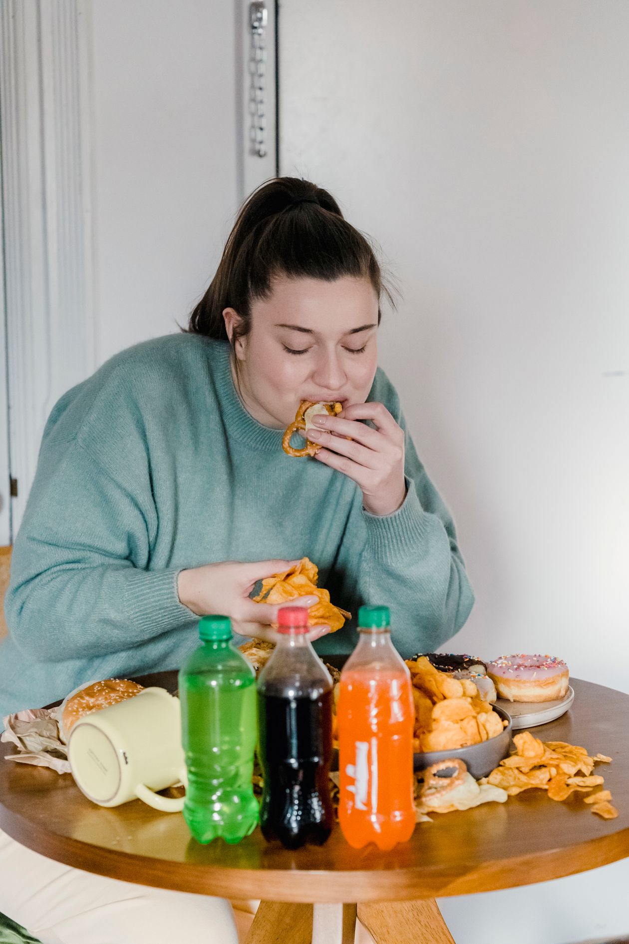 woman eating chips and fast food at a table showing inflammatory food choices that worsen joint pain