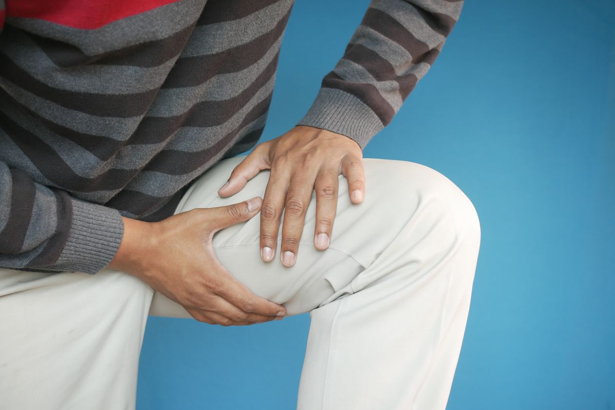 close-up of a man's hands on his knee showing pain or discomfort