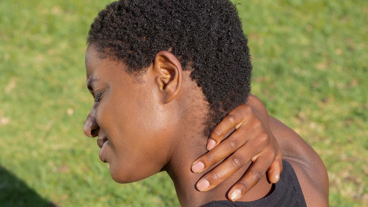 African American woman experiencing neck discomfort outdoors showing cervical pain common in adults over 40