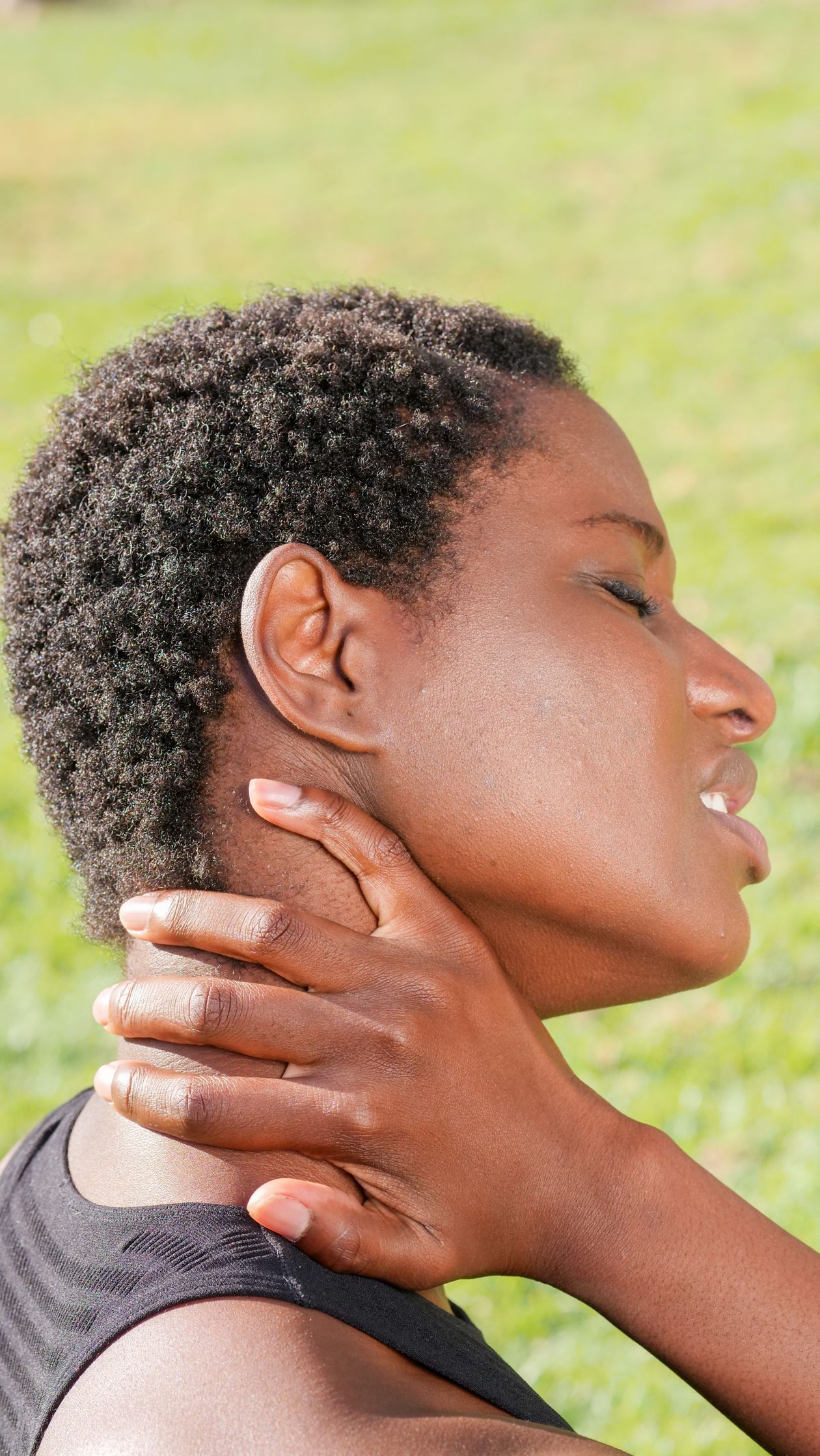 woman holding her neck in discomfort outdoors indicating cervical spine or muscle pain after 40