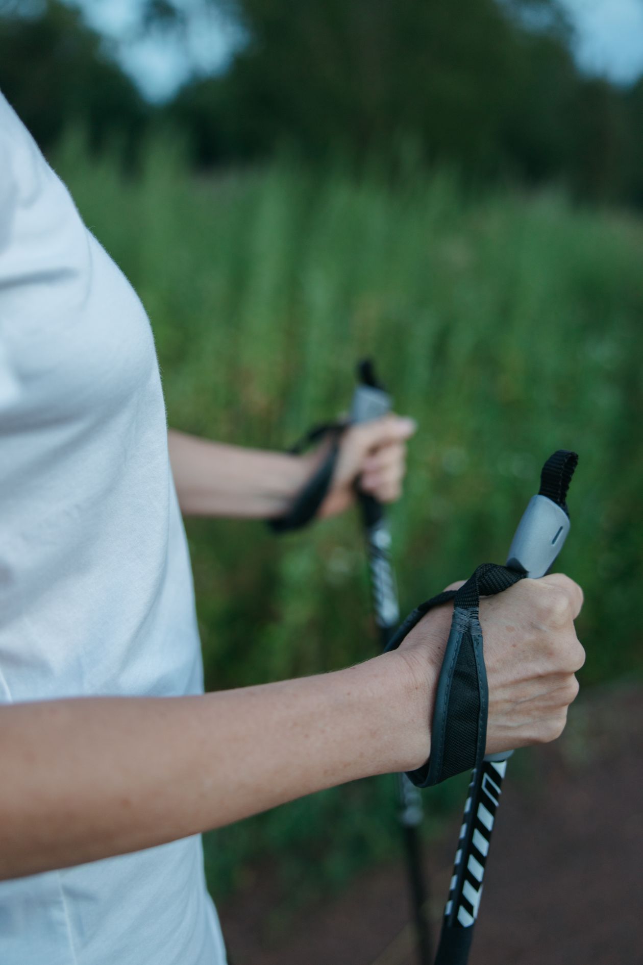 woman using trekking poles for nordic walking in outdoor green setting