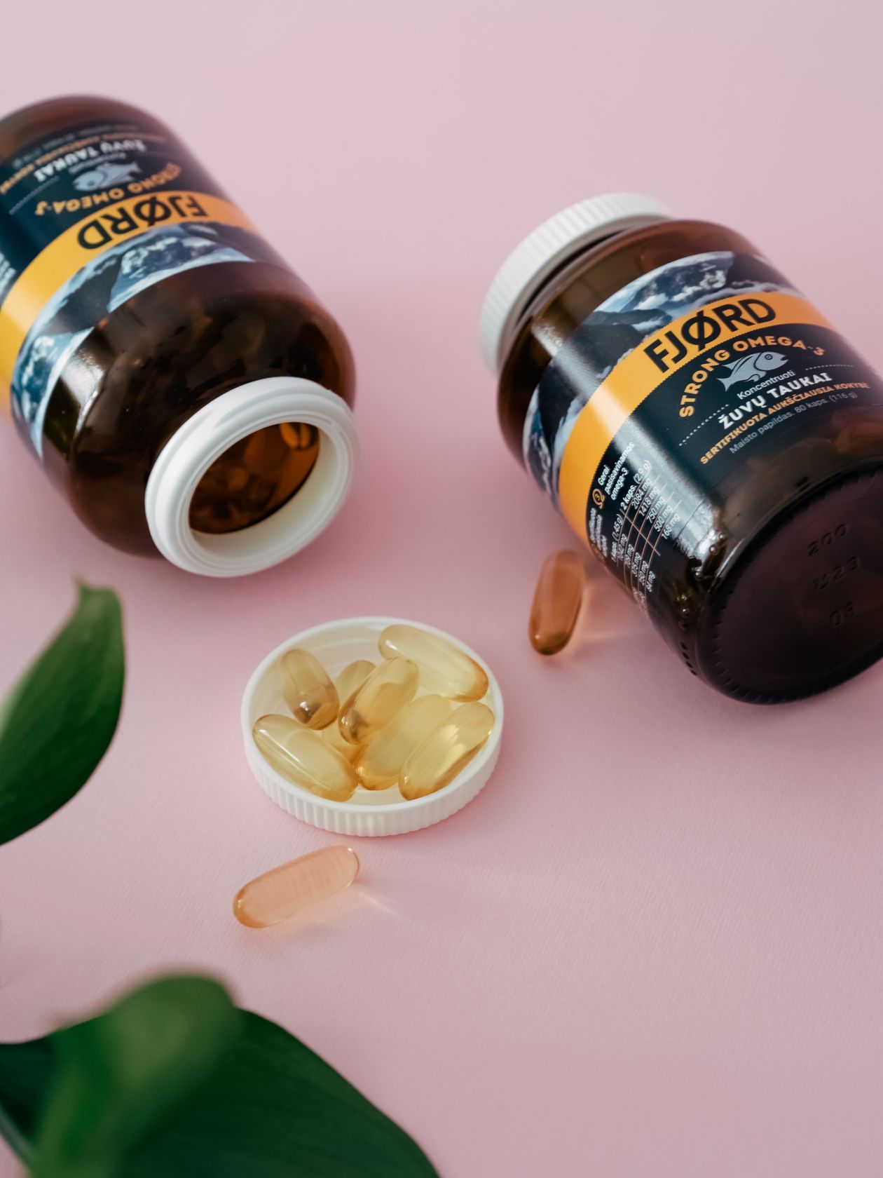 omega-3 supplement bottles and capsules on pink surface illustrating fish oil supplementation for joint health