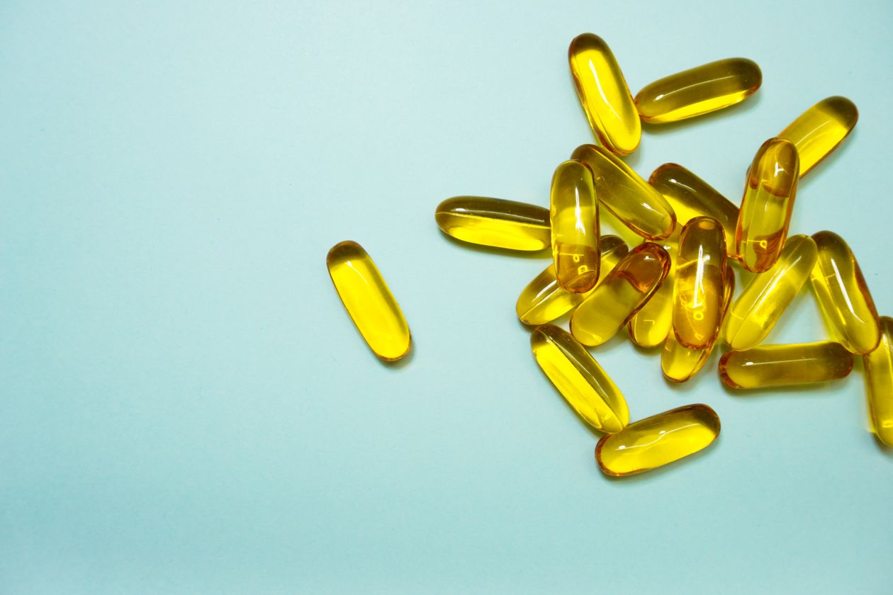 collection of omega-3 fish oil capsules on a light blue surface showing supplement form for joint health