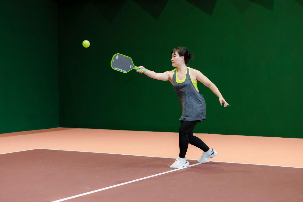 woman playing pickleball on an indoor court showing the sport as active exercise for adults over 40