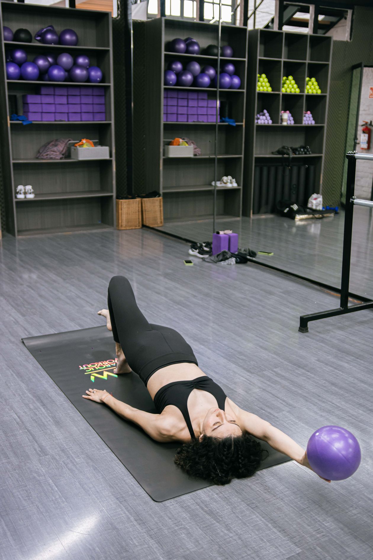 woman exercising with a Pilates ball on a mat in a gym setting showing Pilates core strengthening for back pain