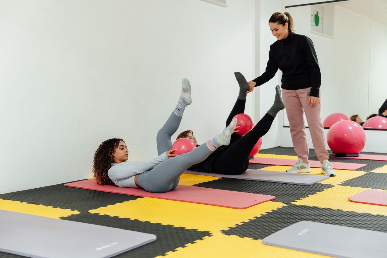 women engaged in a pilates class using exercise balls and yoga mats indoors showing Pilates for back health