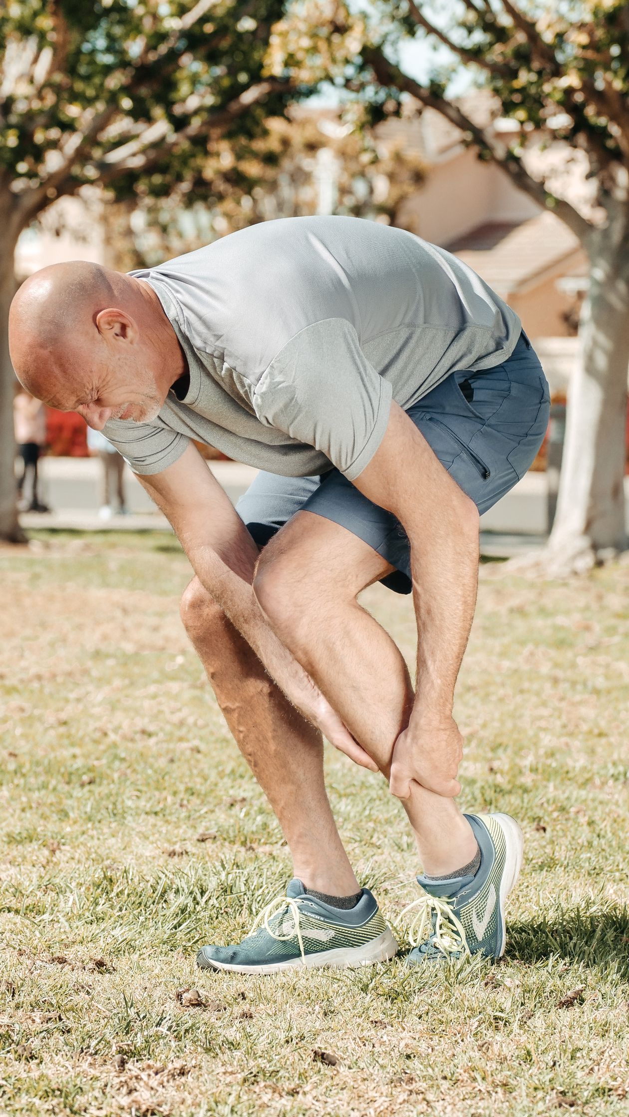 man holding his ankle during outdoor run showing overuse injury common in runners and cyclists over 40