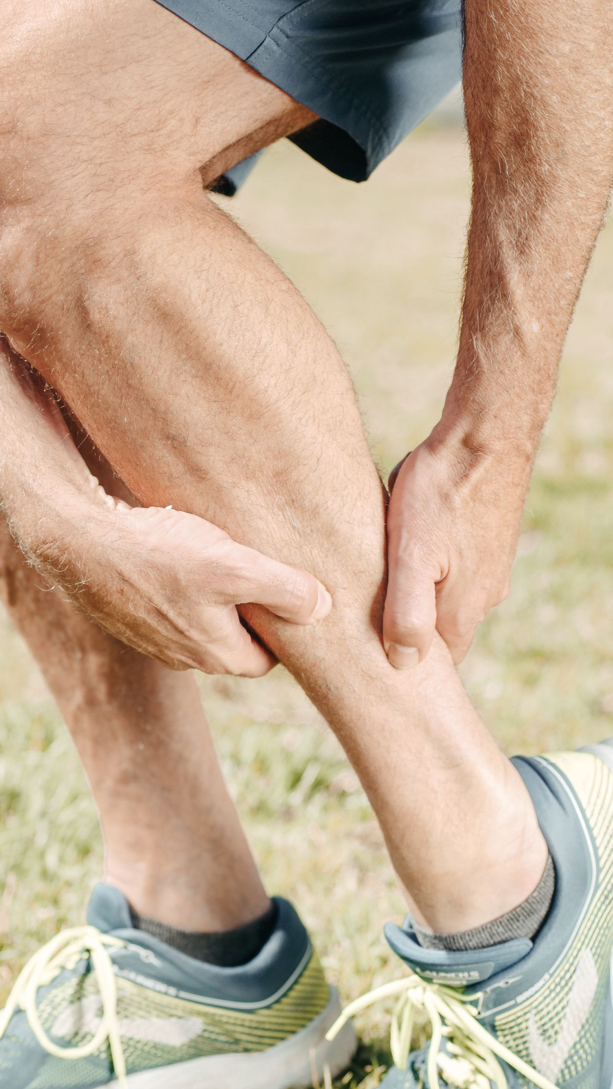 man massaging his calf during outdoor activity showing sciatic nerve pain radiating down the leg