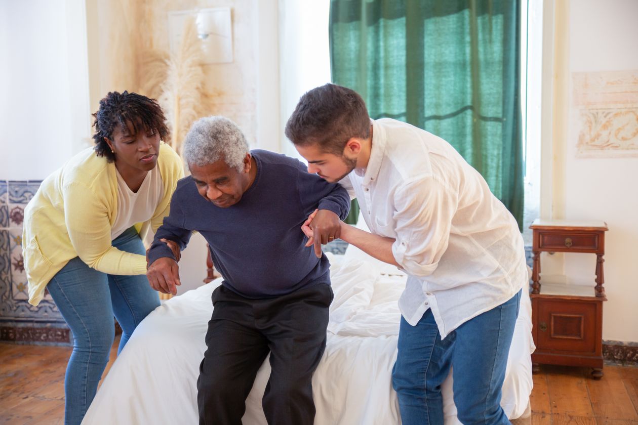elderly man receiving assistance from caregiver at home showing fall prevention support and independence for seniors