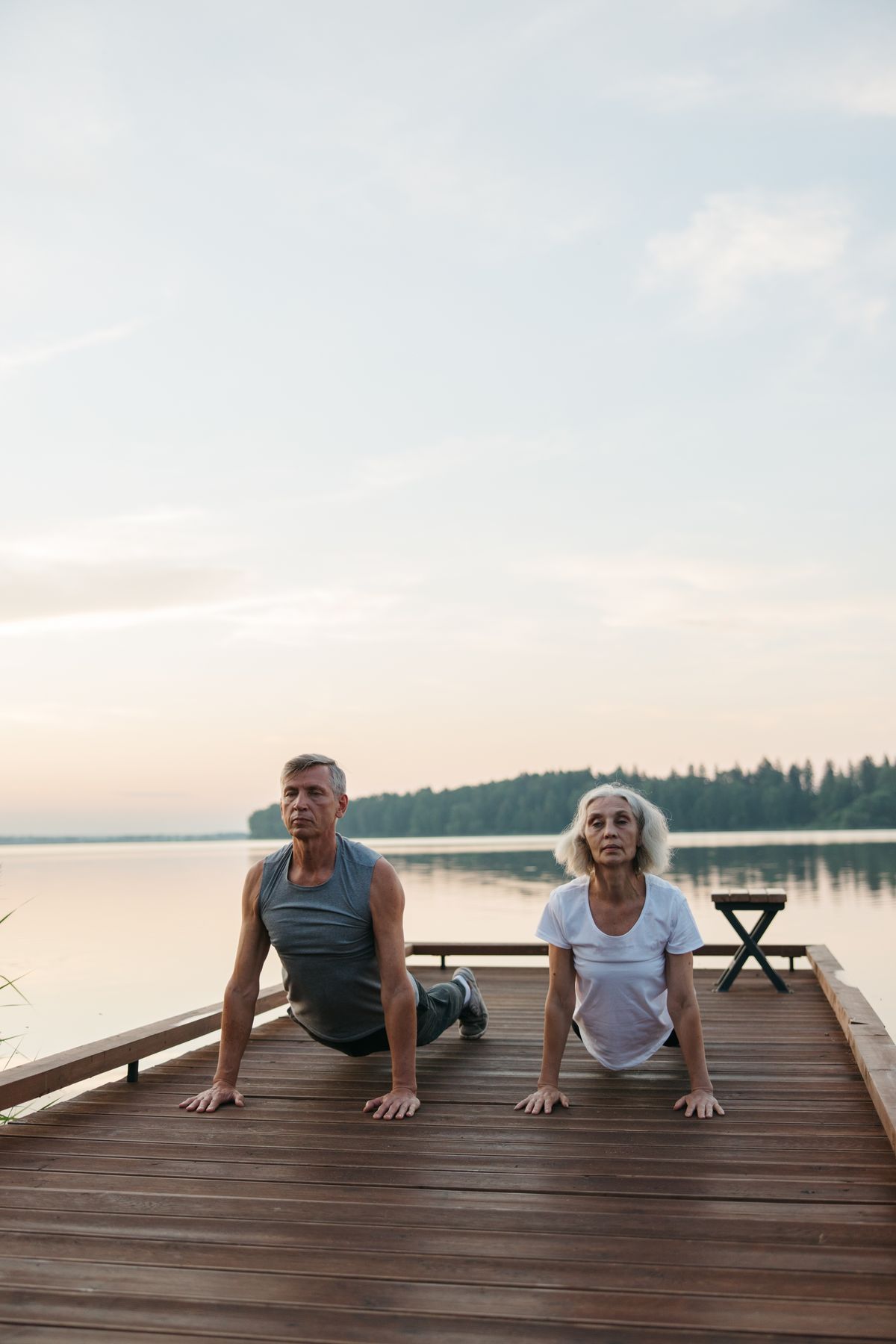 elderly couple doing yoga outdoors by a lake for joint mobility