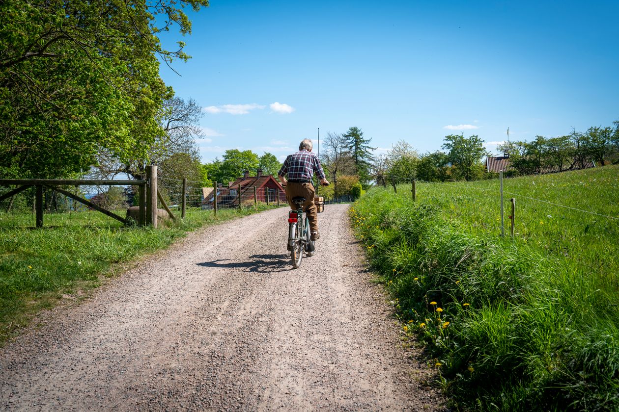 senior adult cycling on a gravel path surrounded by countryside scenery showing active aging through cycling