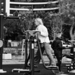 senior adults exercising on outdoor gym equipment in city park