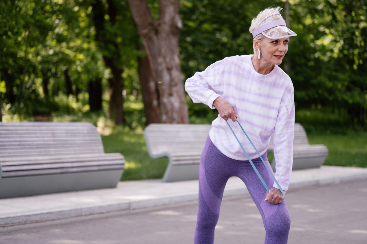 senior woman doing resistance band exercise outdoors in park