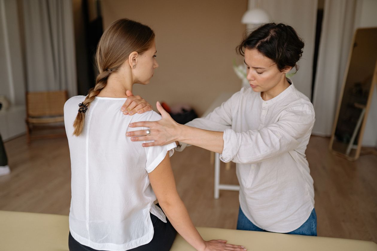 therapist performing shoulder massage on a woman to relieve tension and shoulder pain