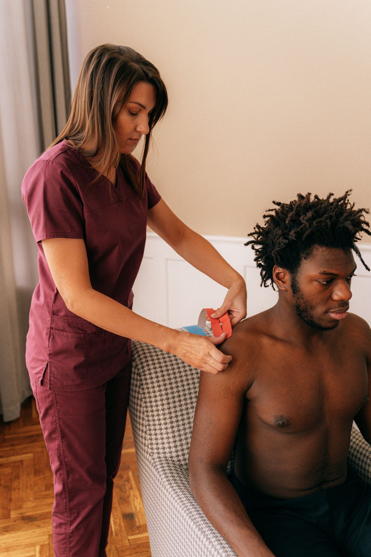 physiotherapist applying kinesiology tape to athlete shoulder for therapeutic support and pain relief showing professional shoulder care