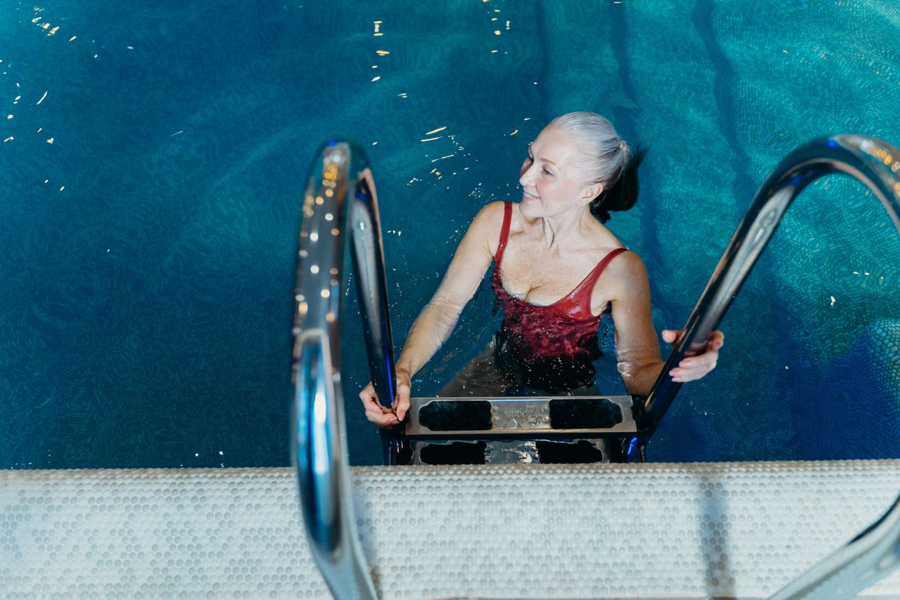 senior woman in swimsuit smiling while at a swimming pool showing water exercise benefits for joint health