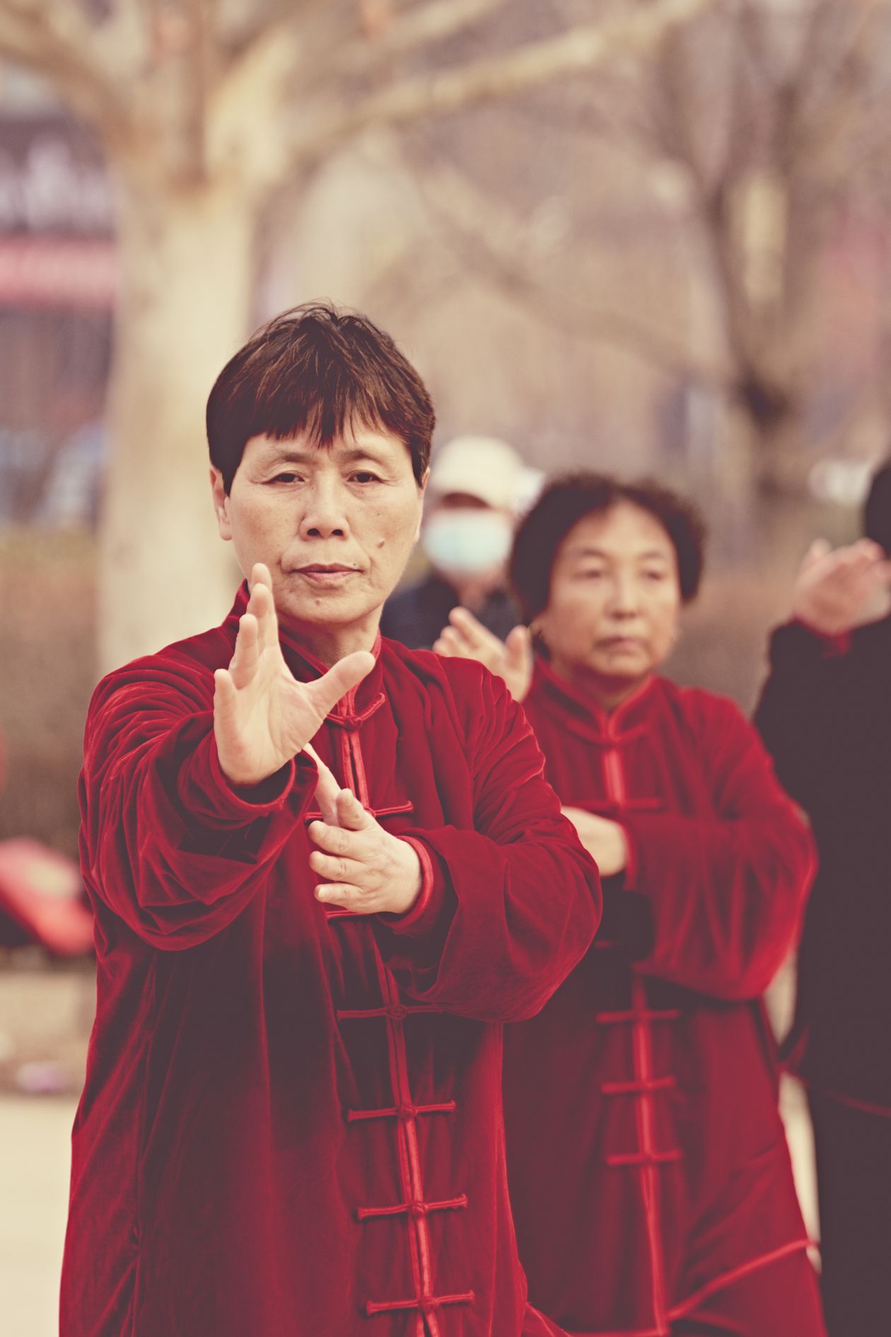 group of people performing tai chi exercises outdoors in traditional attire showing group tai chi practice for wellness