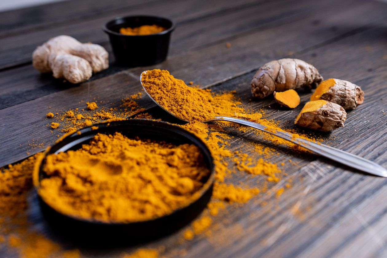 fresh turmeric root and curcumin powder on rustic wooden surface showing natural anti-inflammatory properties