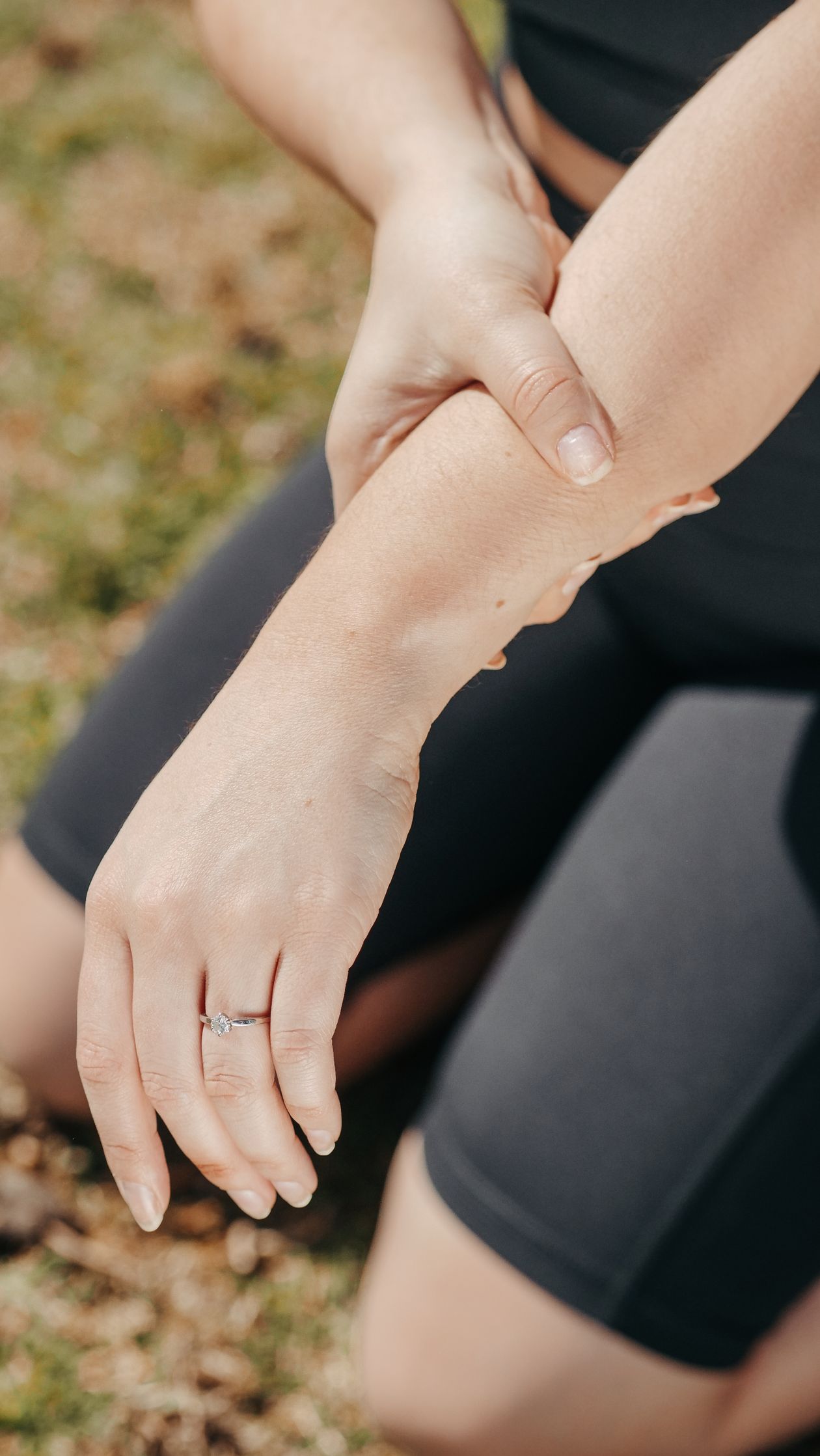 woman holding her wrist in pain outdoors in athletic wear indicating wrist or hand joint discomfort