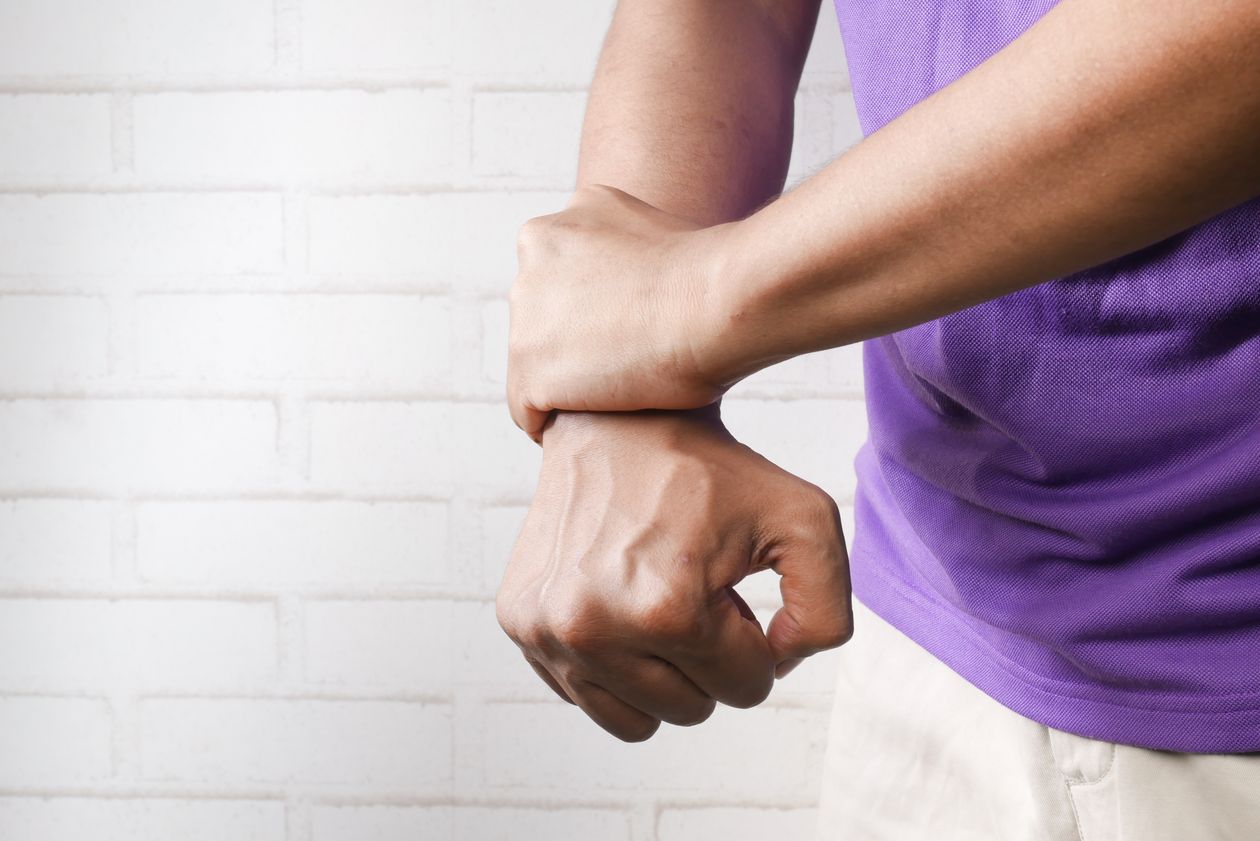 person holding their wrist in pain against a brick wall showing wrist joint discomfort in adults over 40