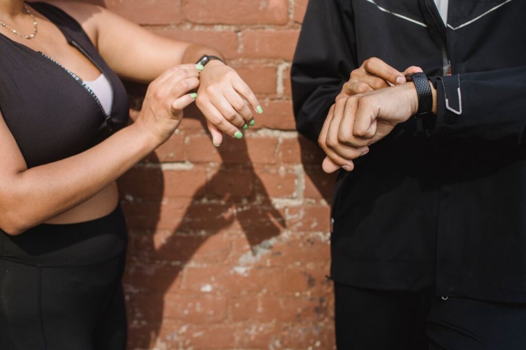 Two people checking their fitness trackers smartwatches outdoors
