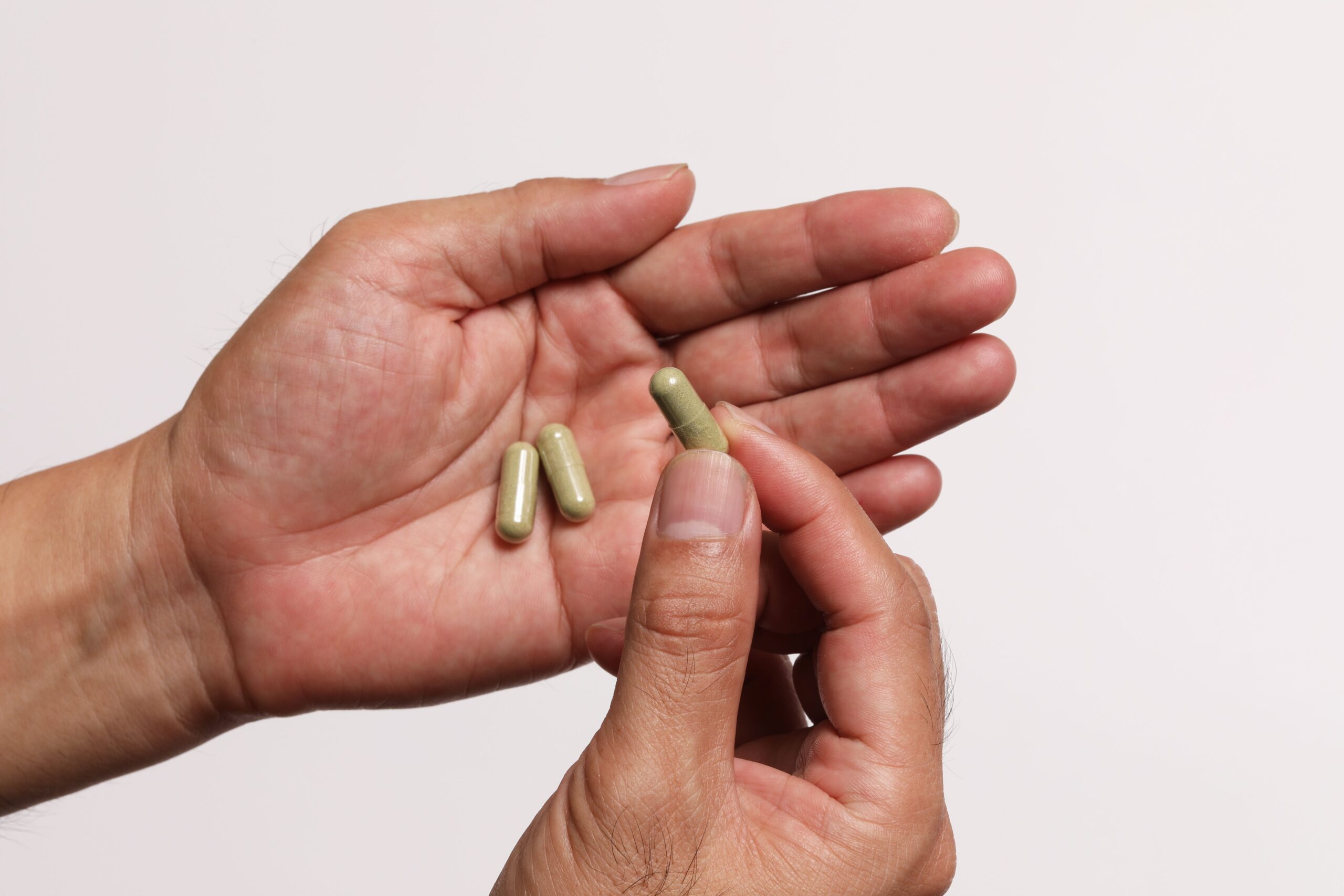 green supplement capsules in hand showing natural herbal formula for joint and mobility support in adults over 40