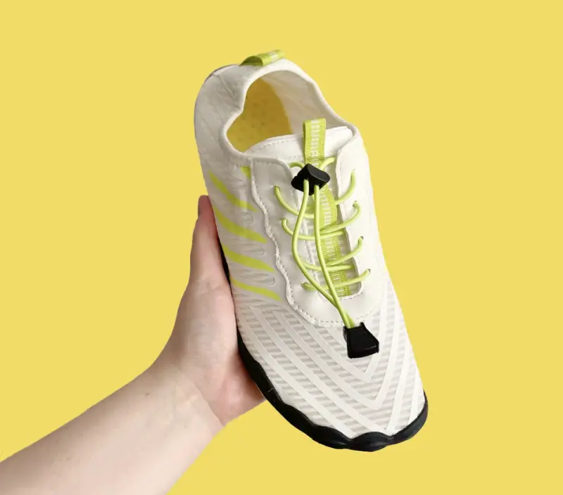 Hand holding Grounded Footwear barefoot shoe showing lightweight flexible construction for natural gait after 40