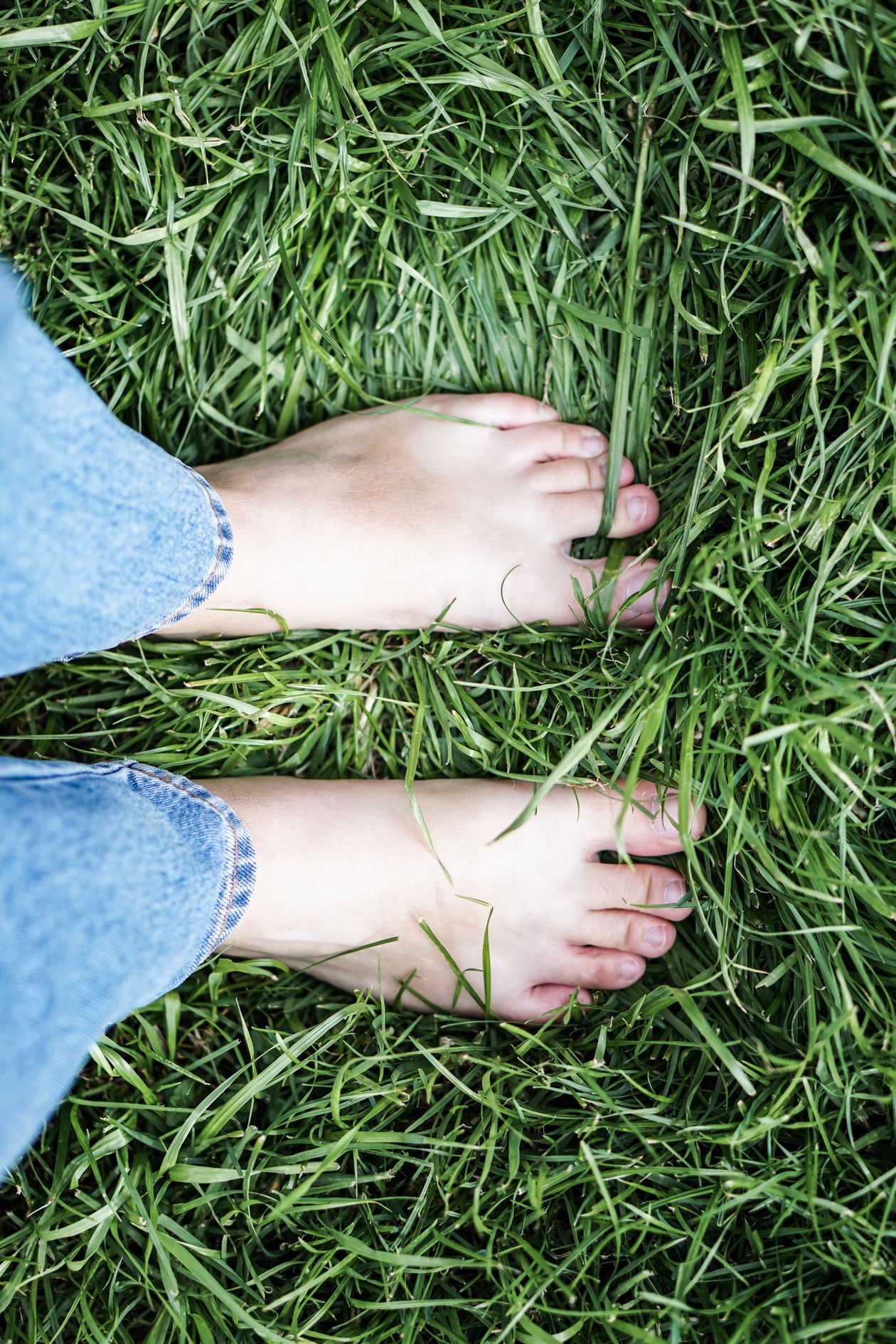 Bare feet standing on green grass representing grounding therapy earthing