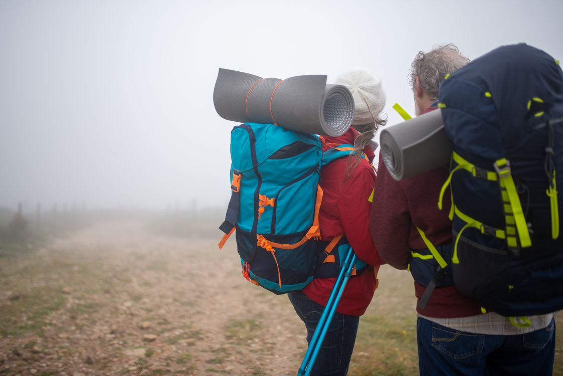Active senior adults hiking mountain trail showing mobility and independence in outdoor activity over 40 with proper knee protection