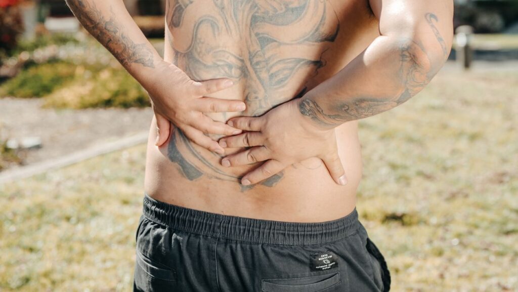 Man holding his lower back in pain outdoors