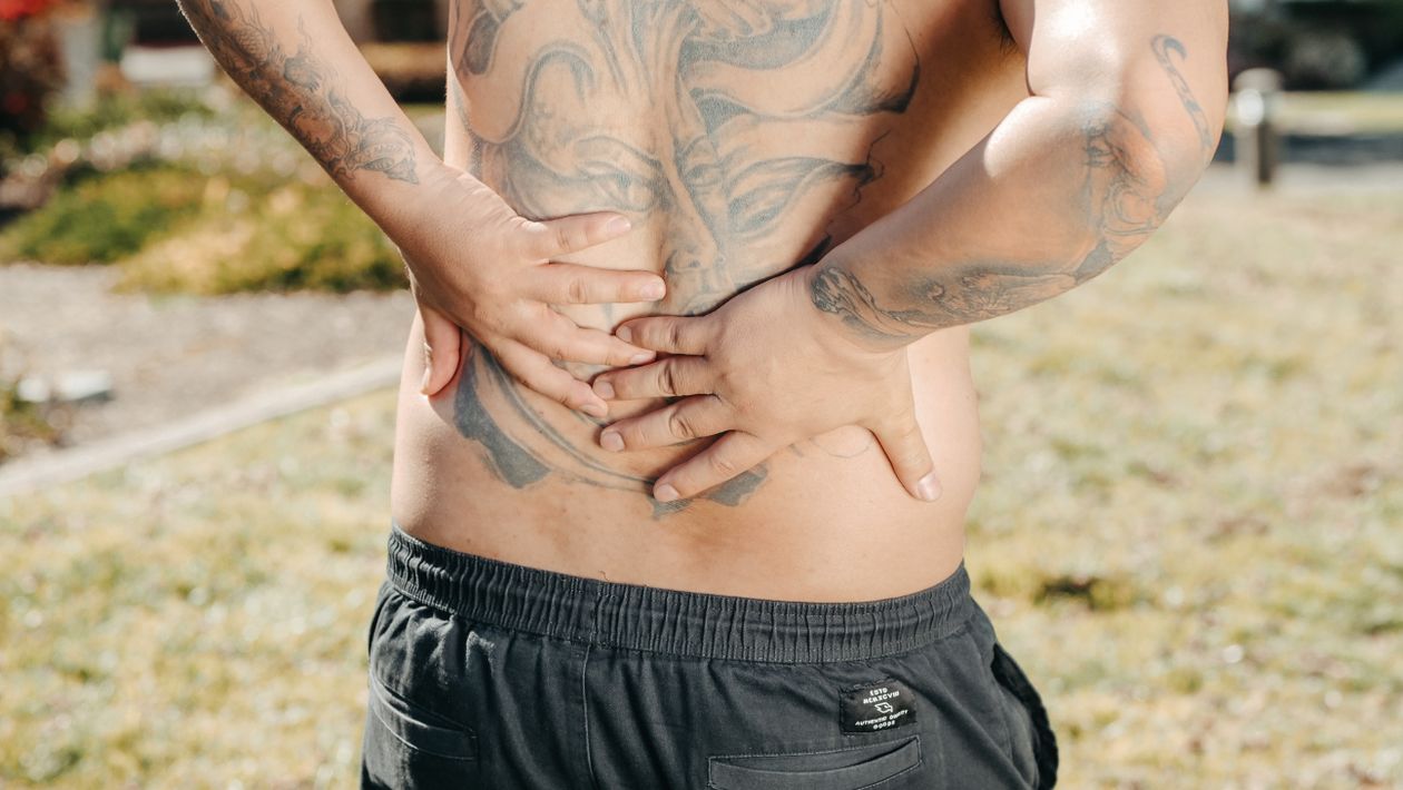 Man holding his lower back in pain outdoors