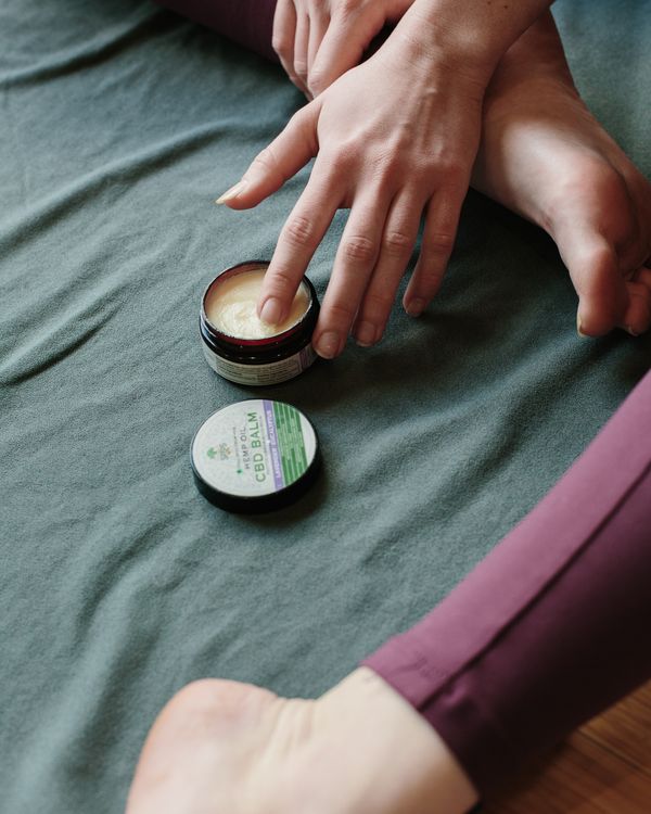Hands applying natural botanical pain relief balm to joint for targeted muscle and joint pain relief