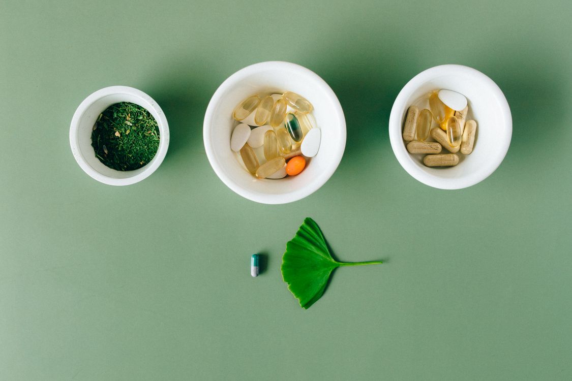 Natural herbal supplements and capsules in ceramic bowls showing MSM and complementary joint health ingredients